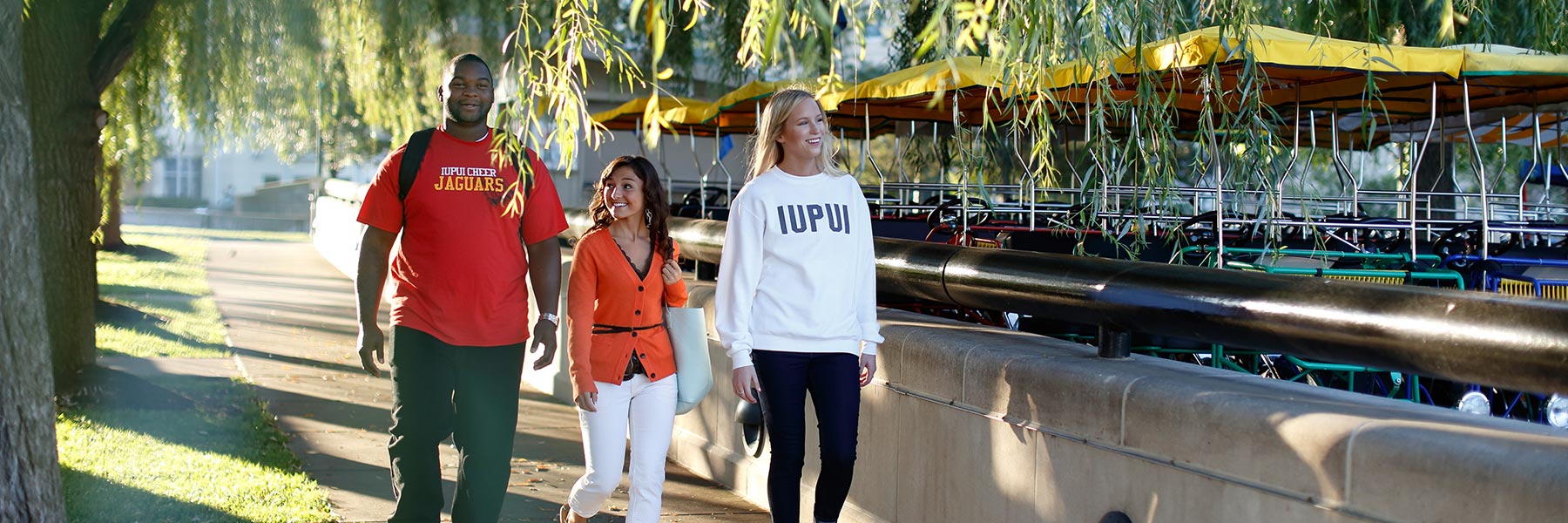 IUPUI students walk down a sidewalk by some trees.
